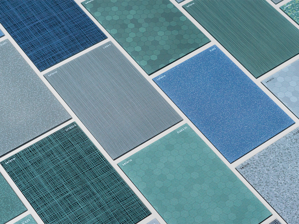 The image shows a collection of tiles, possibly ceramic, in various shades of blue and green with different patterns and textures. Each tile is distinct, suggesting a range of designs likely from the same manufacturer or designer collection.